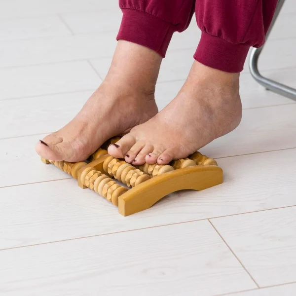 Une personne se tenant debout sur un masseur de pieds en bois.