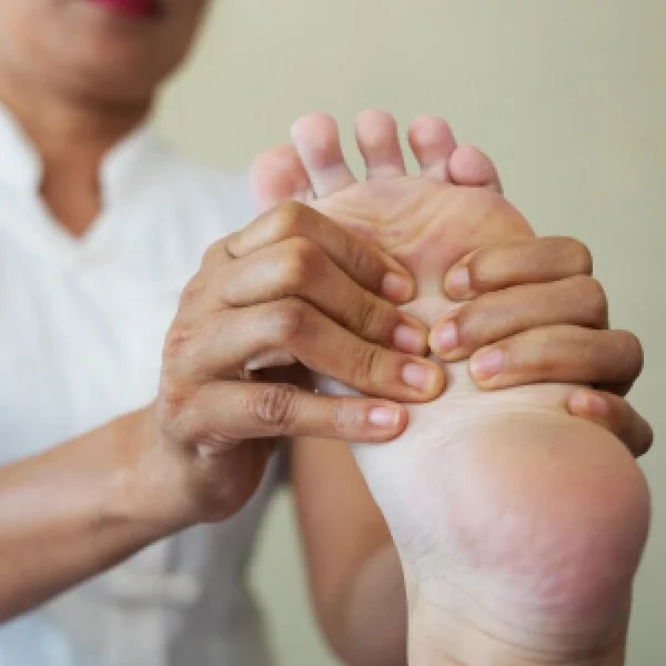 Une femme masse le pied d'une autre personne, créant une atmosphère de détente et de bien-être.